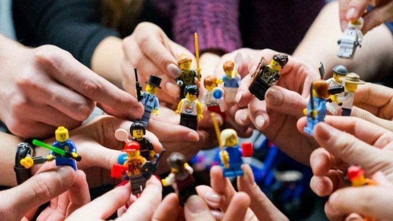 Many people holding different LEGO characters together