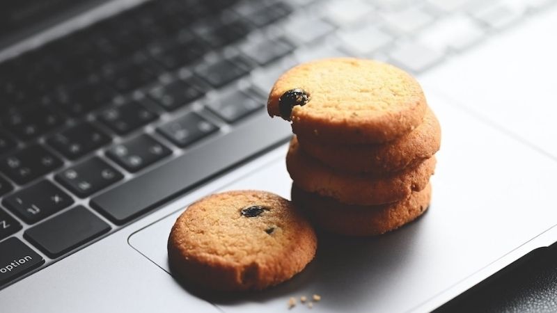 A stack of cookies with a bite taken out of the top one, sitting on a laptop keyboard