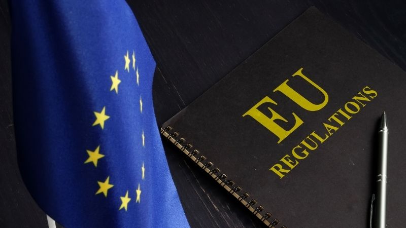 EU flag next to a notebook titled “EU Regulations” on a desk