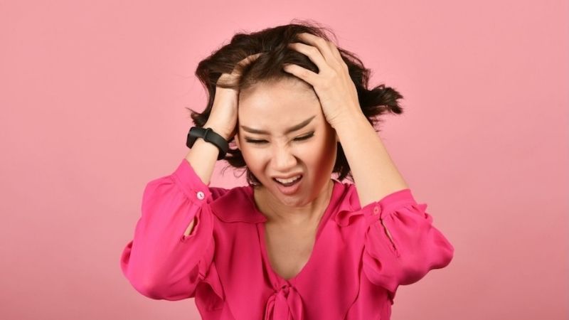 Woman in pink dress with hands on head, conveying distress or emotional turmoil