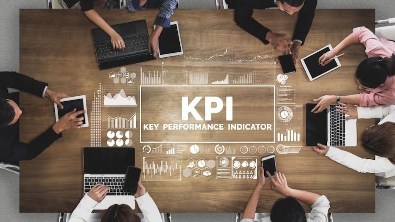 Team of people working around a table with “KPI” displayed in the center