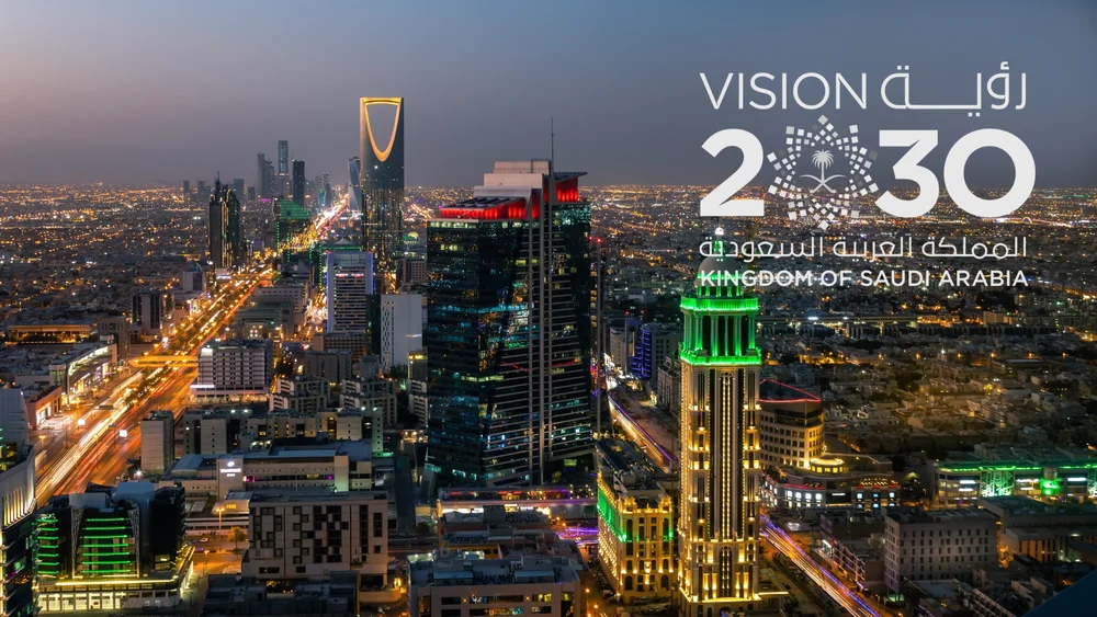 Arabia's Vision 2030 logo against a nighttime cityscape of Riyadh, with the Kingdom of Saudi Arabia name below