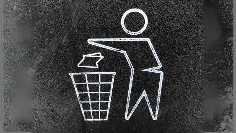 A simple line drawing of a person throwing something into a trash can. The image is in black and white on a textured background