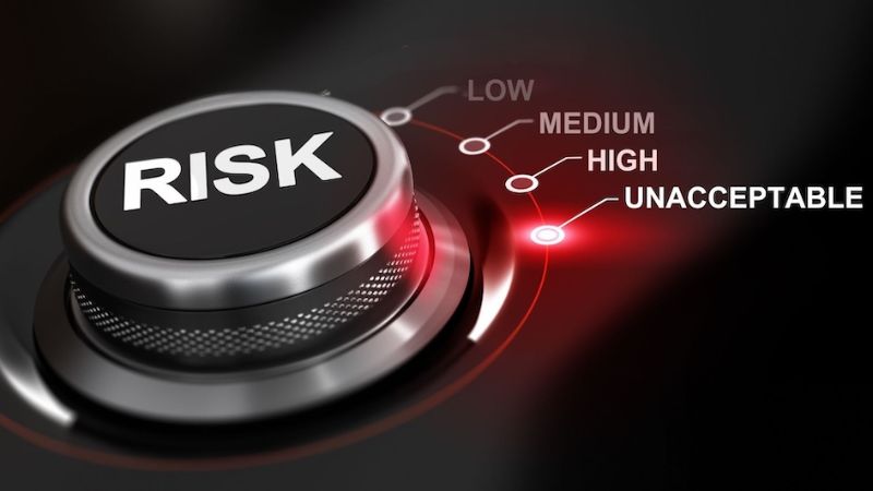 Dial with "RISK" label showing low, medium, and high settings against a red-lit background, representing risk assessment