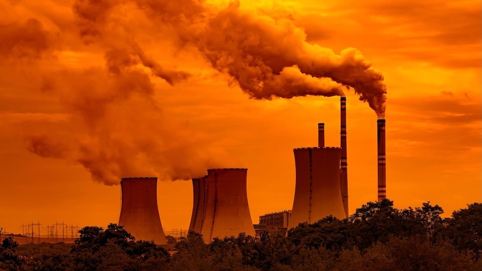 Industrial smokestacks emitting thick smoke against orange sky, depicting environmental degradation.