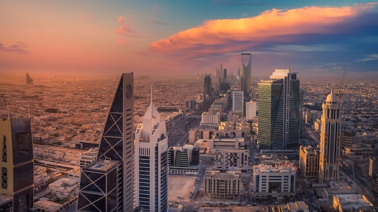 A panoramic view of Riyadh, Saudi Arabia at sunset, featuring skyscrapers and a dramatic sky