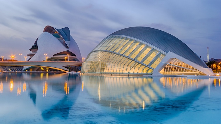 A futuristic architectural complex of buildings reflected in a large pool of water