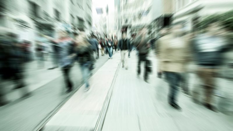 Blurred crowd walking down a busy city street