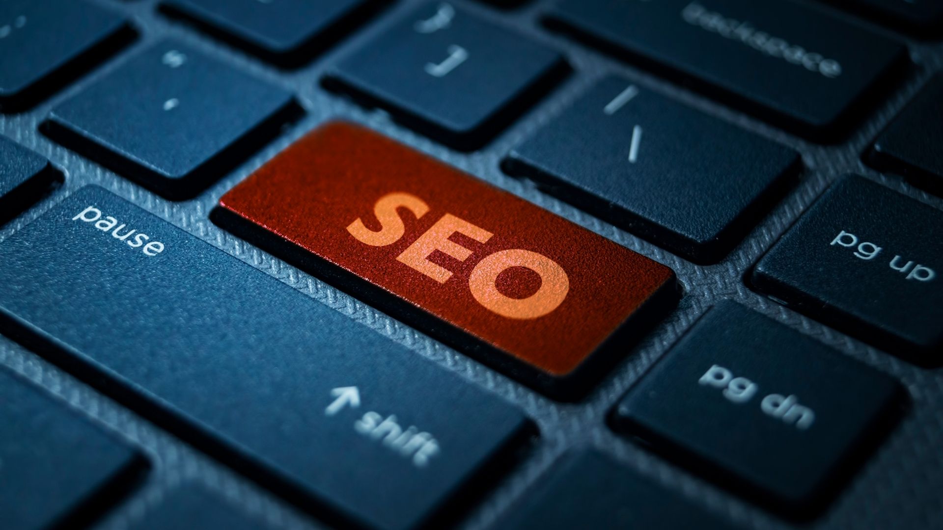 A close-up of a keyboard with a red key labeled "SEO" among black keys, symbolizing search engine optimization focus